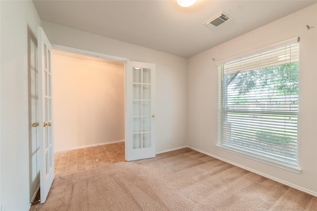 spare room with light colored carpet and french doors