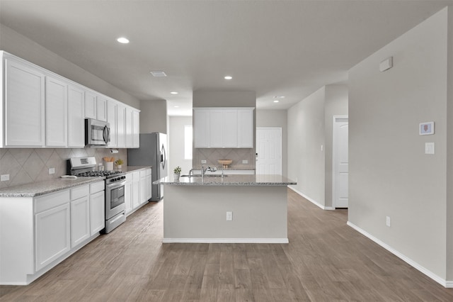 kitchen featuring light stone countertops, appliances with stainless steel finishes, and white cabinets