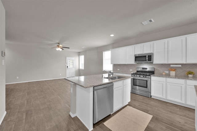 kitchen with stainless steel appliances, an island with sink, light hardwood / wood-style flooring, and white cabinets