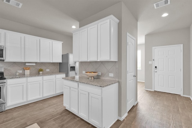 kitchen featuring light stone counters, stainless steel appliances, light hardwood / wood-style floors, and white cabinets