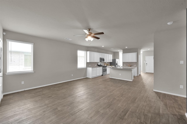 unfurnished living room with ceiling fan and dark hardwood / wood-style flooring