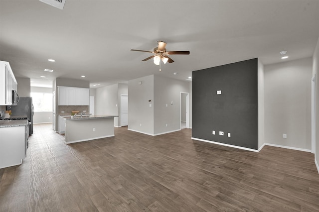 unfurnished living room featuring ceiling fan and dark hardwood / wood-style flooring