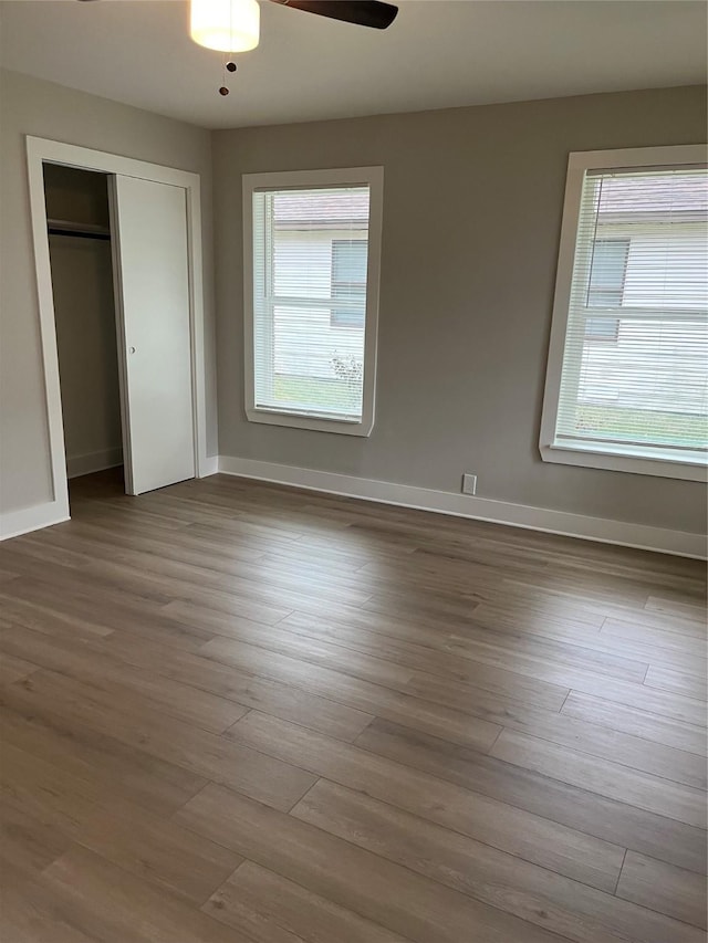 unfurnished bedroom featuring multiple windows, a closet, ceiling fan, and light wood-type flooring