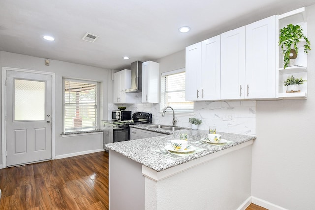 kitchen with wall chimney exhaust hood, black electric range oven, sink, and white cabinets