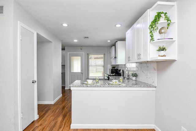 kitchen with white cabinetry, sink, light stone counters, and decorative backsplash