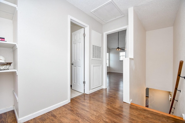 hallway with hardwood / wood-style floors and a textured ceiling