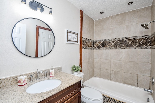 full bathroom with vanity, tiled shower / bath, a textured ceiling, and toilet