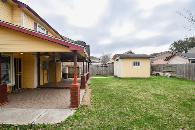 view of yard featuring ceiling fan, a storage shed, and a patio