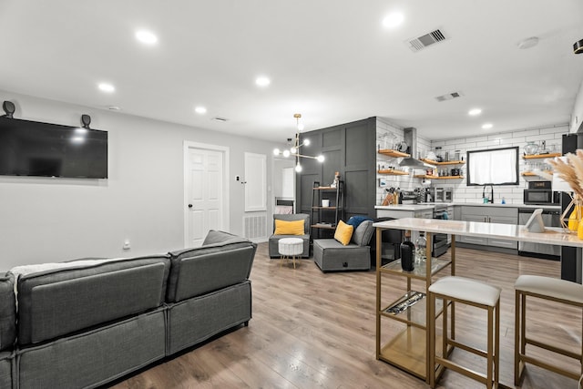 living room with sink, a chandelier, and light hardwood / wood-style floors