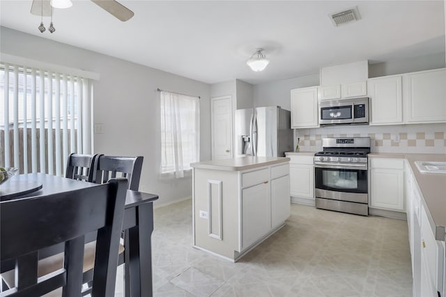 kitchen featuring a kitchen island, white cabinetry, appliances with stainless steel finishes, and backsplash