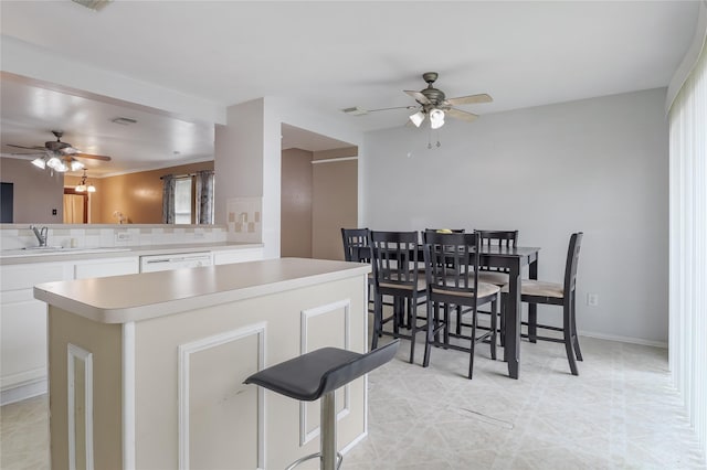 kitchen featuring white cabinetry, sink, a breakfast bar area, stainless steel dishwasher, and kitchen peninsula