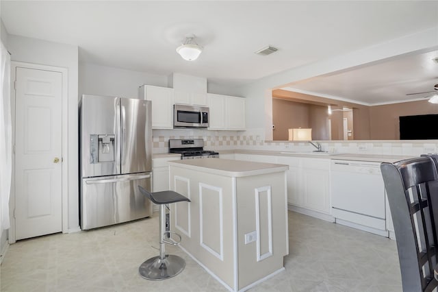 kitchen featuring stainless steel appliances, a kitchen island, sink, and white cabinets