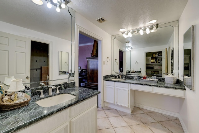 49 Briar Hollow Ln Unit 302, Houston, TX 77027 - full bath featuring a sink, a textured ceiling, tile patterned flooring, two vanities, and visible vents