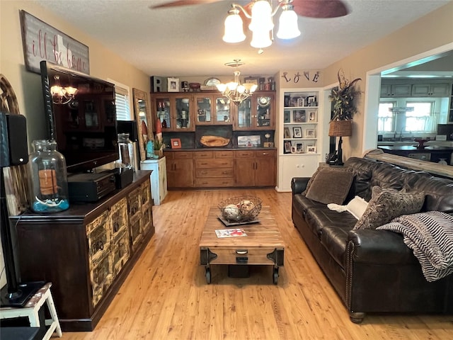 living room featuring sink, ceiling fan with notable chandelier, a textured ceiling, and light hardwood / wood-style floors