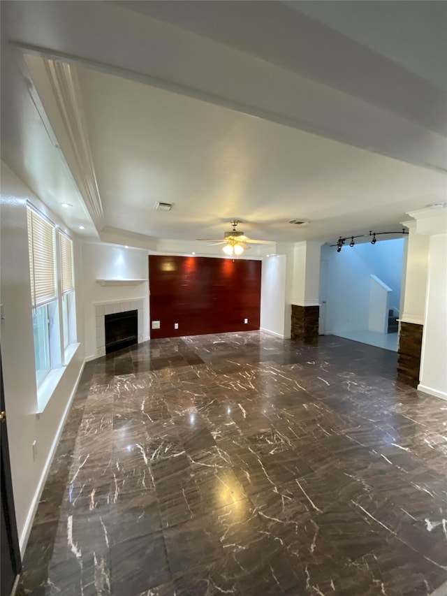 unfurnished living room with a tiled fireplace, rail lighting, and ceiling fan