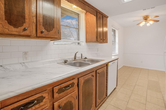 kitchen with sink, light tile patterned floors, ceiling fan, white dishwasher, and decorative backsplash