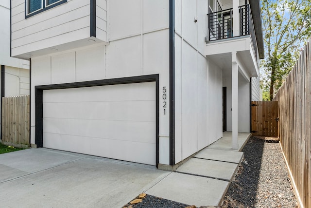 view of side of home with a garage and a balcony