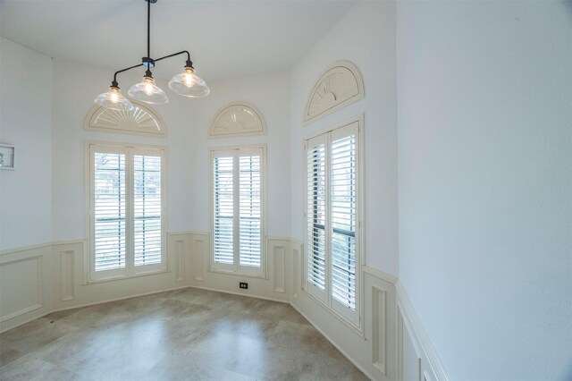 unfurnished dining area with wainscoting and a decorative wall