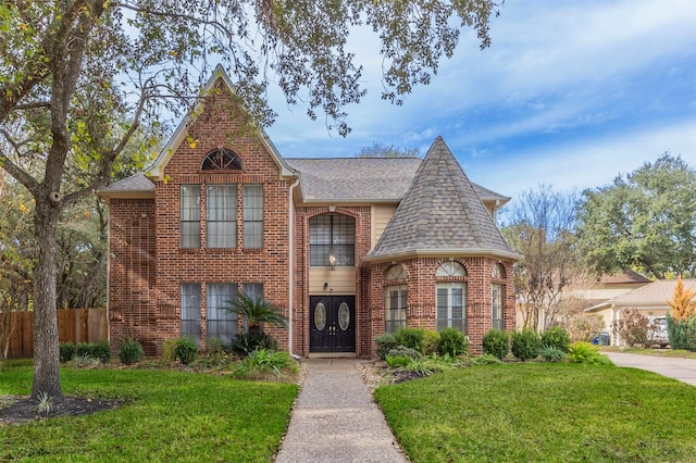 view of front of property with brick siding, a front yard, and fence