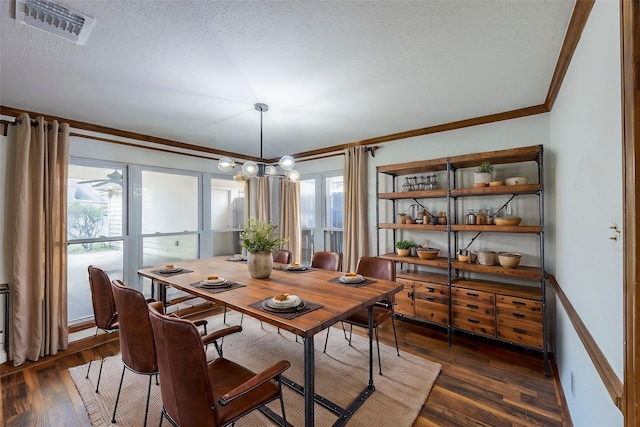 dining area featuring dark wood-type flooring, a wealth of natural light, visible vents, and crown molding