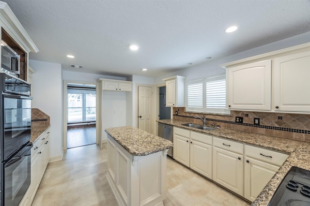 kitchen with light stone counters, a sink, visible vents, white cabinetry, and black appliances