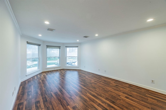 unfurnished room with ornamental molding, dark wood-type flooring, visible vents, and baseboards