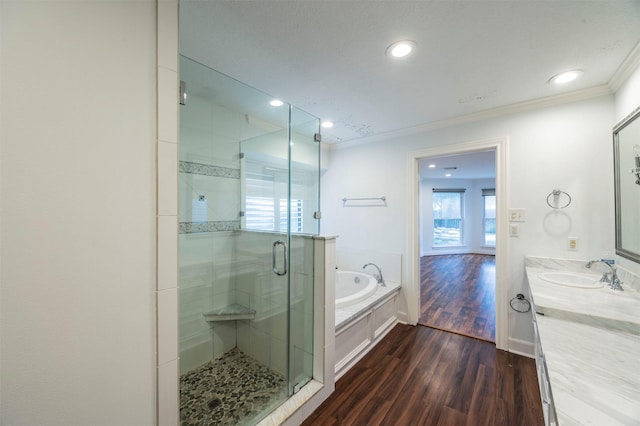 bathroom featuring a stall shower, ornamental molding, wood finished floors, a garden tub, and vanity