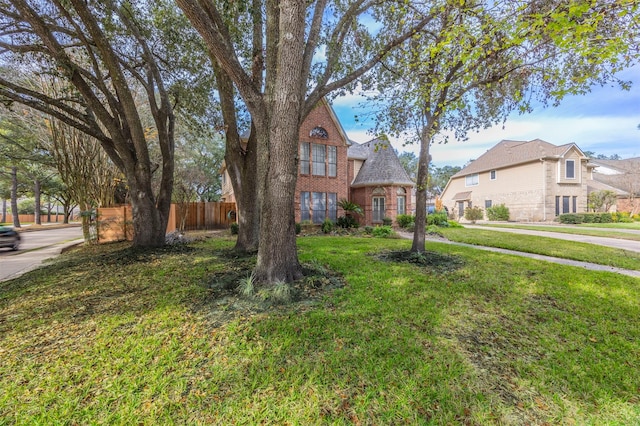 view of front of property featuring a front yard, brick siding, and fence