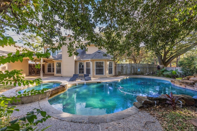 view of swimming pool with a fenced backyard, a pool with connected hot tub, and a patio