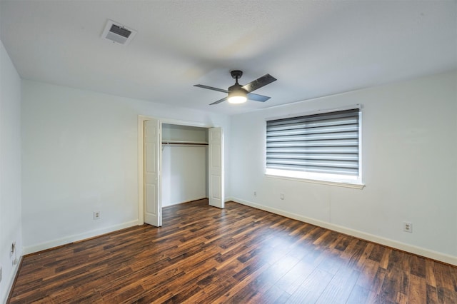 unfurnished bedroom featuring baseboards, visible vents, a ceiling fan, dark wood finished floors, and a closet