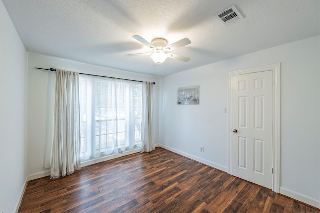 empty room with a textured ceiling, dark wood finished floors, and visible vents