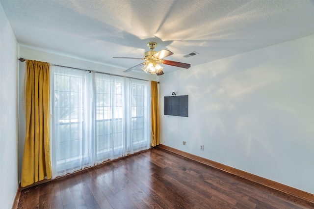 empty room with a textured ceiling, ceiling fan, dark wood-style flooring, visible vents, and baseboards