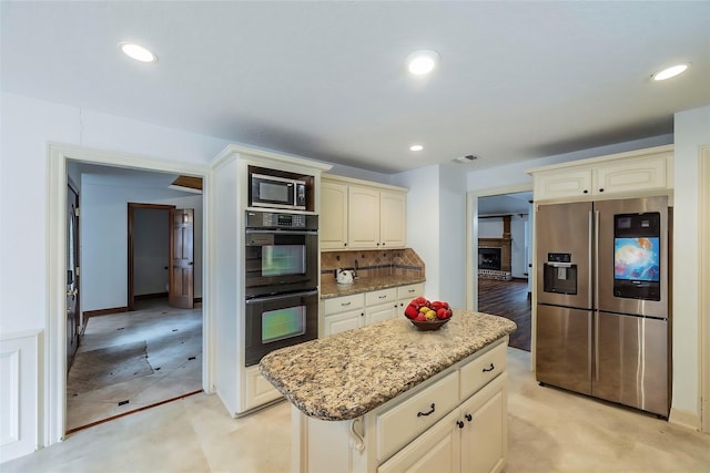 kitchen with cream cabinetry, stainless steel appliances, recessed lighting, tasteful backsplash, and light stone countertops