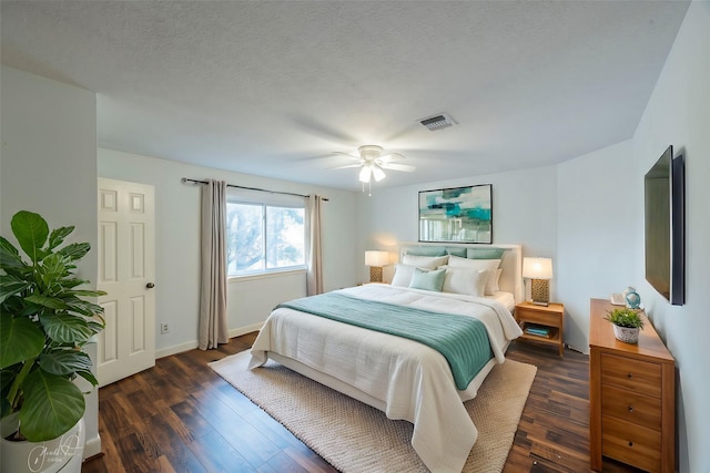 bedroom with dark wood-style flooring, visible vents, ceiling fan, a textured ceiling, and baseboards