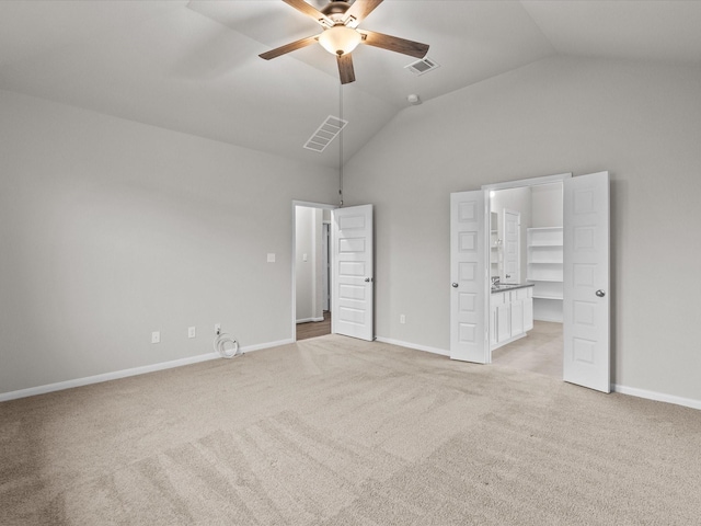 unfurnished bedroom featuring a spacious closet, vaulted ceiling, light colored carpet, and ceiling fan