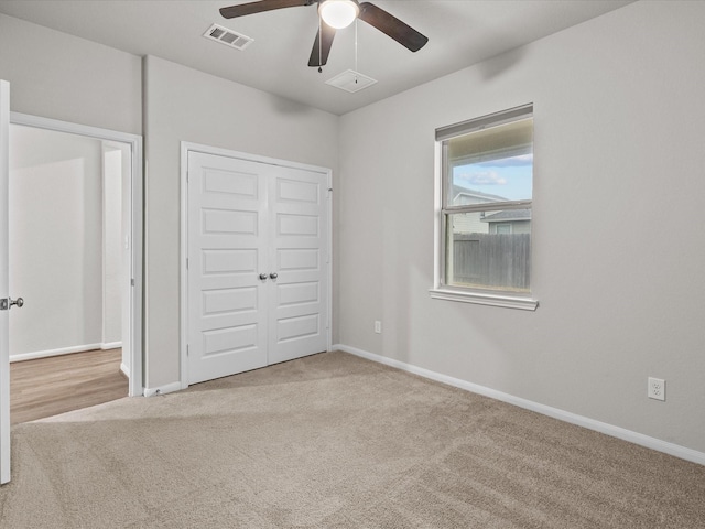 unfurnished bedroom featuring light colored carpet, ceiling fan, and a closet