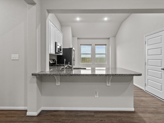 kitchen with white cabinetry, appliances with stainless steel finishes, a kitchen bar, and kitchen peninsula