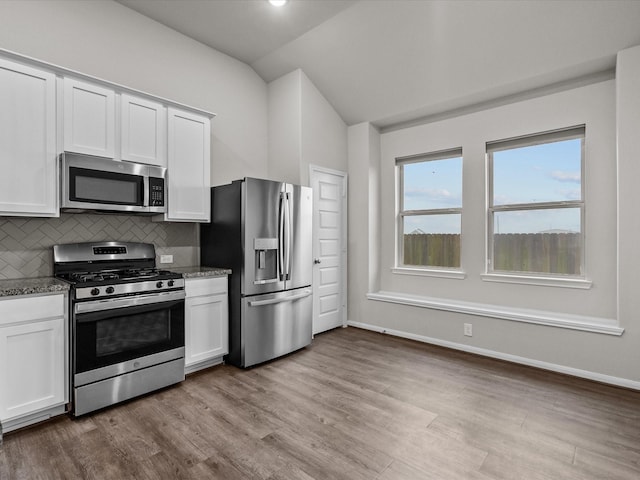 kitchen featuring decorative backsplash, lofted ceiling, appliances with stainless steel finishes, and white cabinets