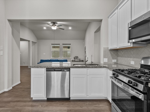 kitchen featuring sink, appliances with stainless steel finishes, white cabinetry, stone countertops, and kitchen peninsula