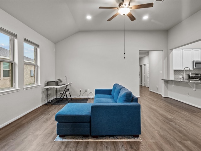 living area with baseboards, wood finished floors, and vaulted ceiling