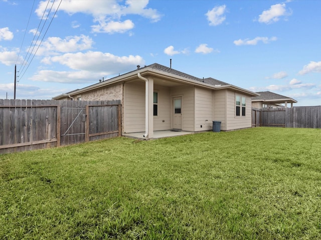 back of house featuring a patio area, a lawn, brick siding, and a fenced backyard