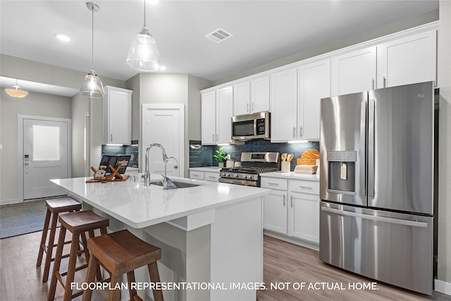 kitchen with appliances with stainless steel finishes, sink, hanging light fixtures, and white cabinets