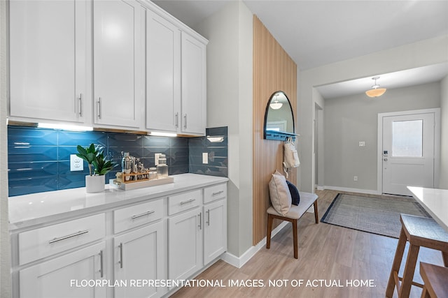 kitchen featuring white cabinetry, pendant lighting, light hardwood / wood-style flooring, and backsplash