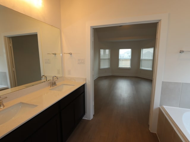 134 Spring Rose Dr, Magnolia, TX 77354 - bathroom featuring wood finished floors, double vanity, and a relaxing tiled tub