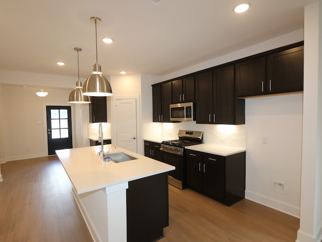 134 Spring Rose Dr, Magnolia, TX 77354 - kitchen with appliances with stainless steel finishes, light wood-style floors, light countertops, a kitchen island with sink, and recessed lighting