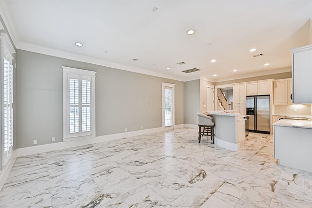 kitchen with stainless steel refrigerator with ice dispenser, a center island, a breakfast bar, and a wealth of natural light