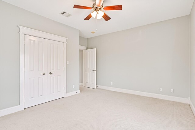 unfurnished bedroom featuring light colored carpet, ceiling fan, and a closet