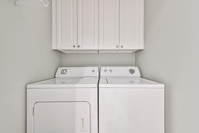 washroom with cabinets and washing machine and clothes dryer