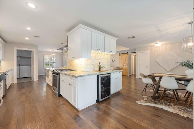 kitchen featuring white cabinetry, hanging light fixtures, a barn door, stainless steel range with gas cooktop, and beverage cooler