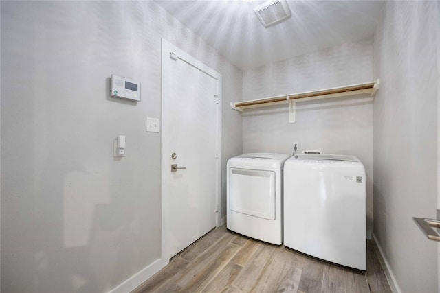 laundry room with light hardwood / wood-style flooring and washer and clothes dryer